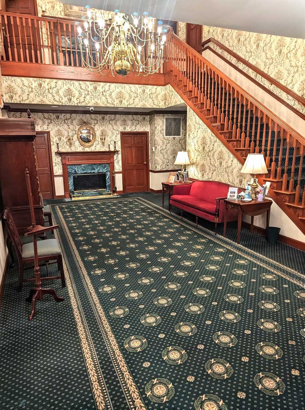 A well-lit foyer featuring an elegant chandelier and wooden stairs.